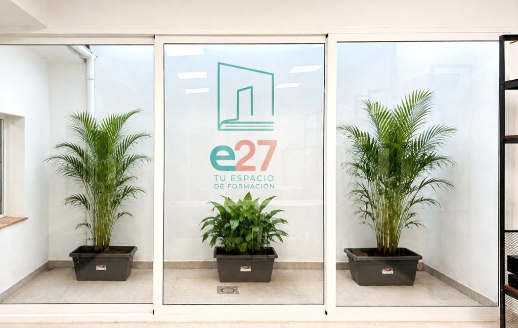Patio de luces de Espacio27 en Bellavista (Sevilla) con el logo de Espacio27 en la pared y plantas